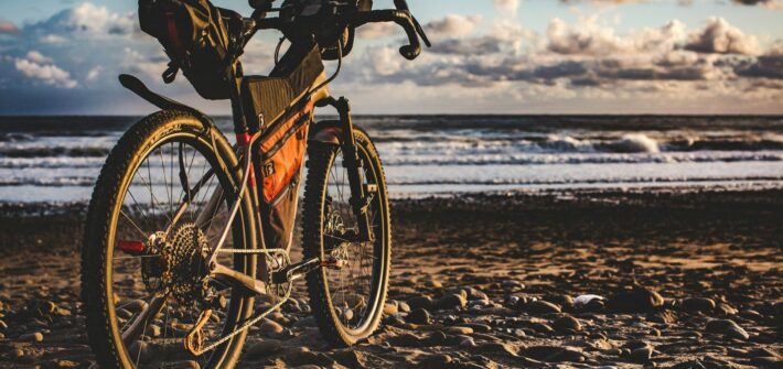 Bike with frame, seat and handlebar bags on a beach at sunset