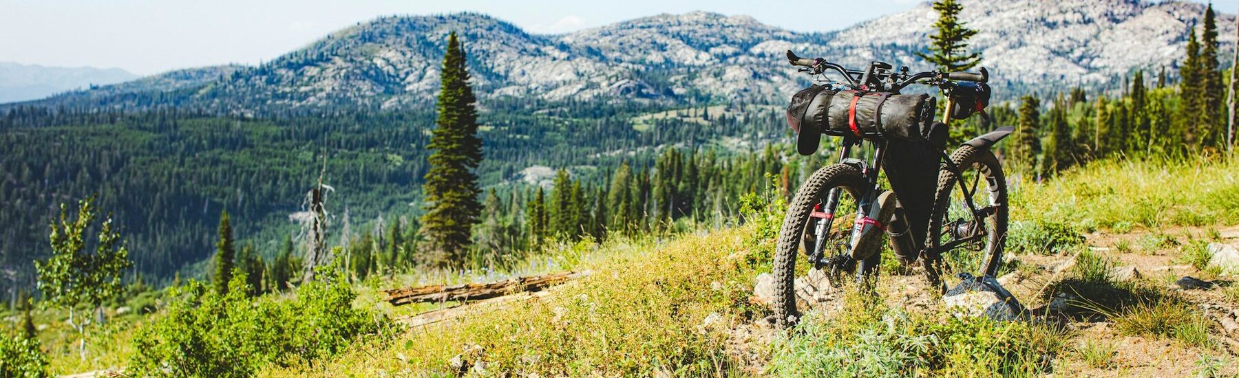 Loaded bike standing in a mountain meadow with peaks behind