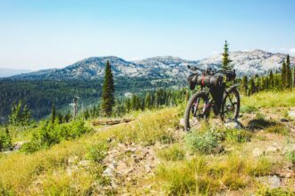 Loaded bike standing in a mountain meadow with peaks behind