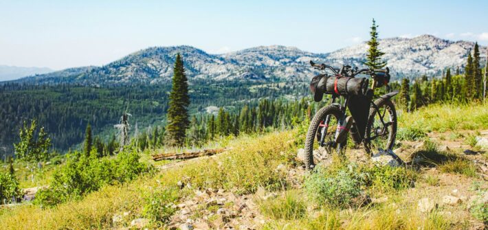 Loaded bike standing in a mountain meadow with peaks behind