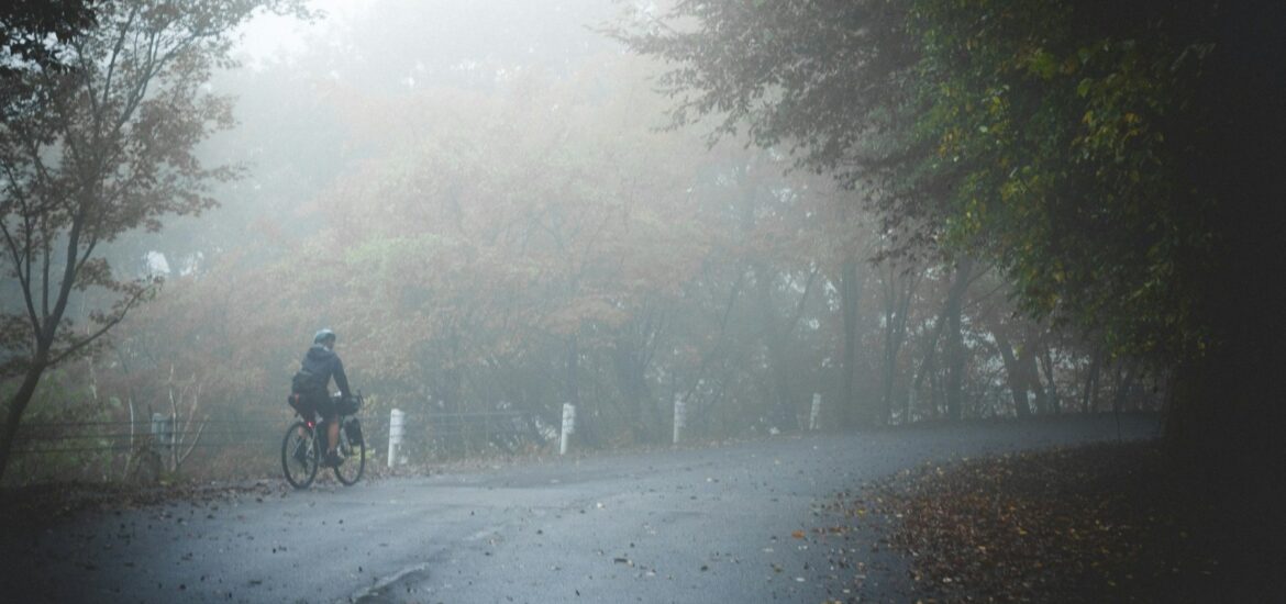 Small figure of a cyclist on a road disappearing into fog
