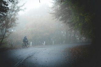 Small figure of a cyclist on a road disappearing into fog