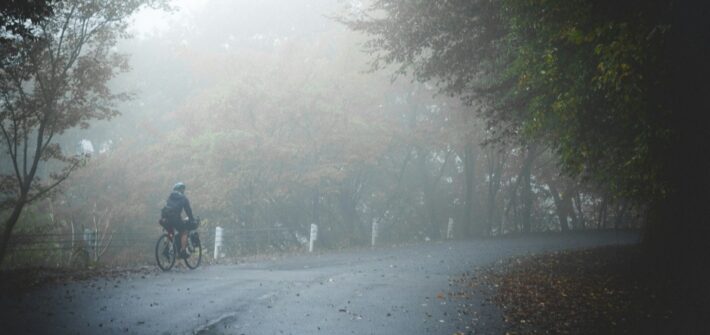 Small figure of a cyclist on a road disappearing into fog