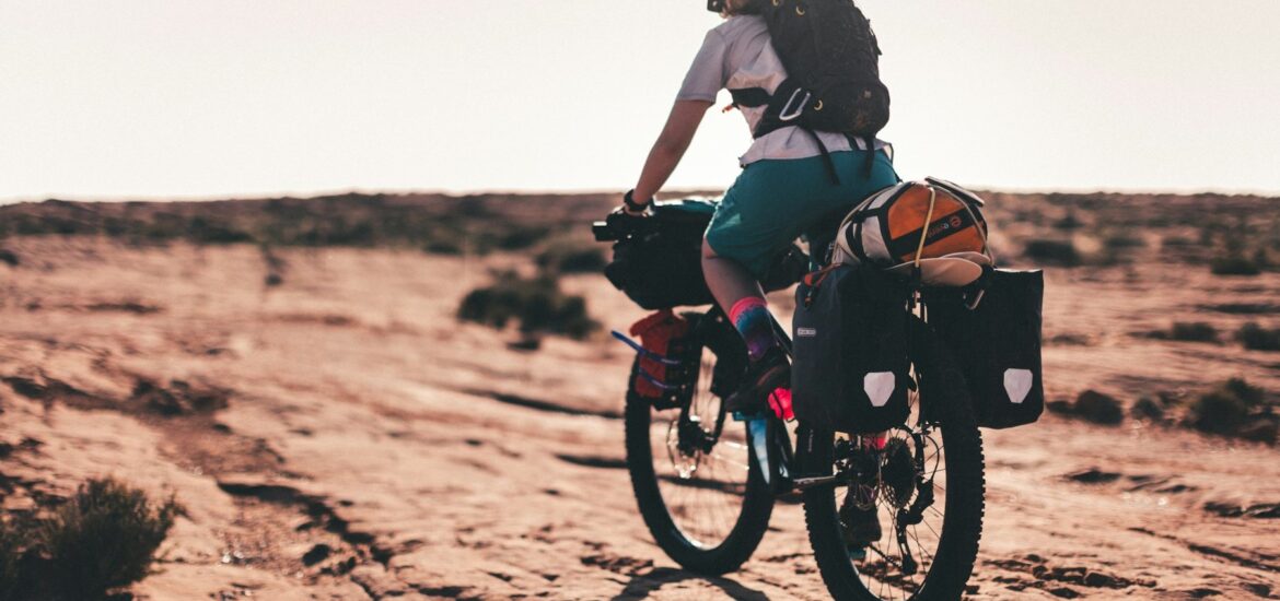 Cyclist on a loaded bike crossing red desert slickrock