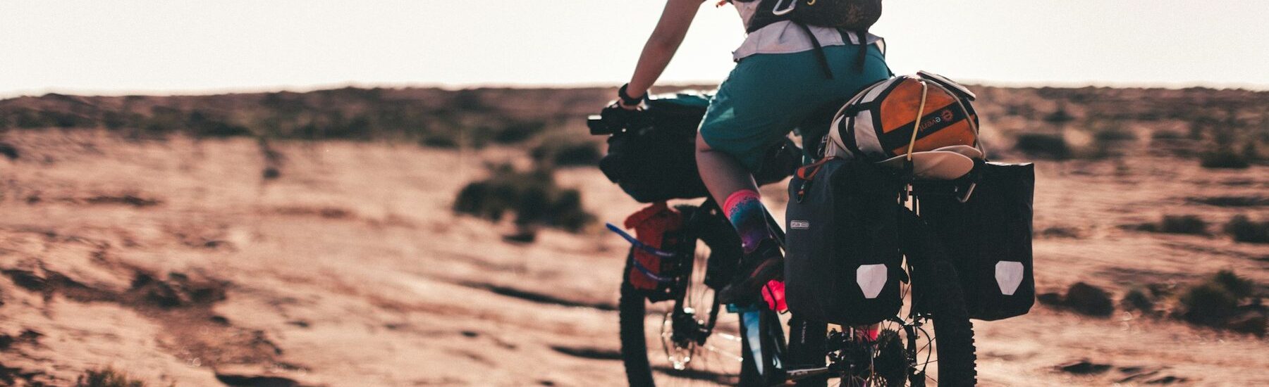 Cyclist on a loaded bike crossing red desert slickrock