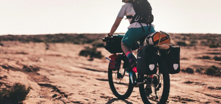 Cyclist on a loaded bike crossing red desert slickrock