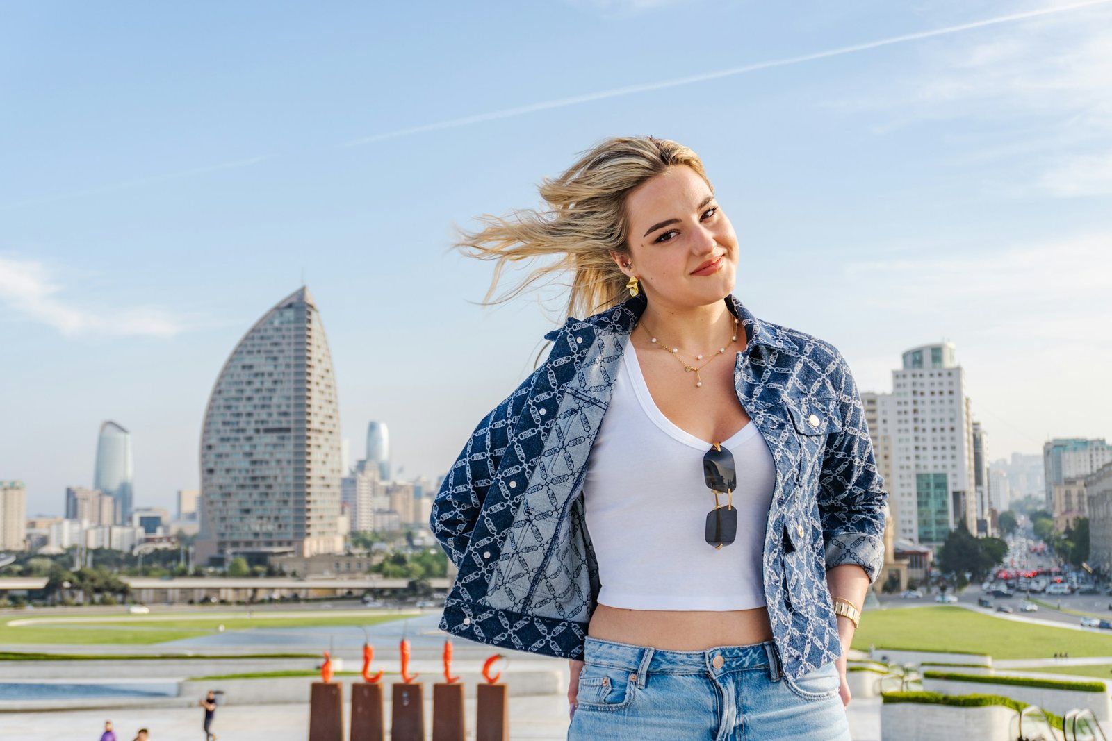 Smiling woman in a denim jacket with city towers behind her