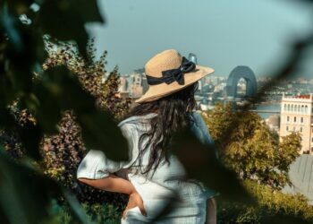 Woman in a straw hat looking over the city from a shady garden