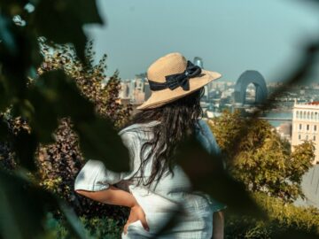 Woman in a straw hat looking over the city from a shady garden