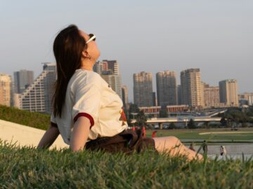 Woman relaxing on a grassy slope in front of the city skyline