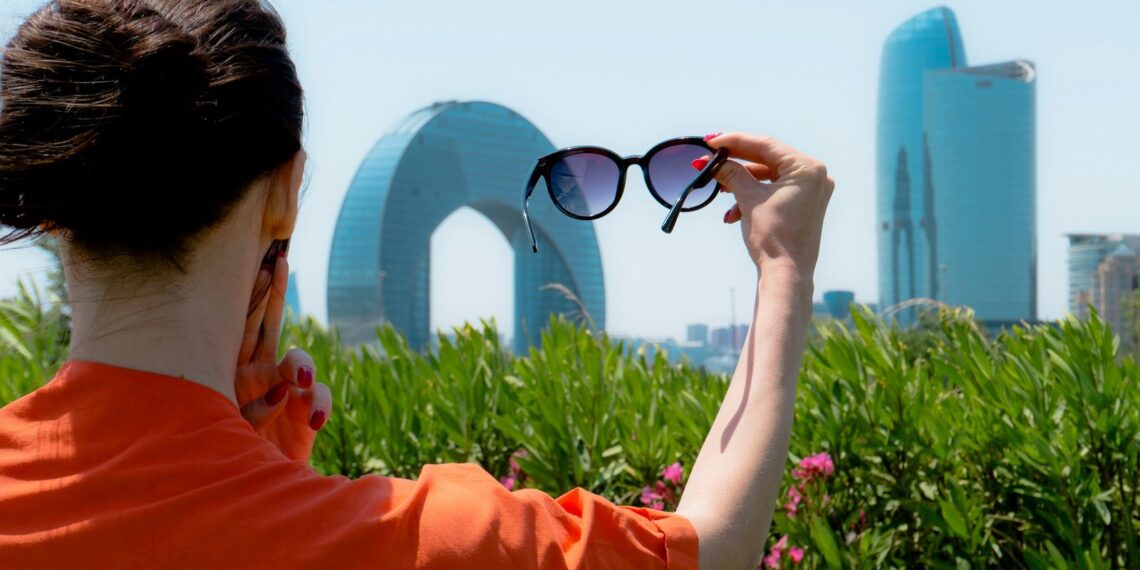 Woman holding up sunglasses against the city skyline