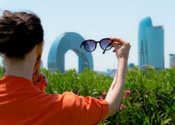Woman holding up sunglasses against the city skyline