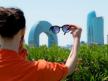 Woman holding up sunglasses against the city skyline