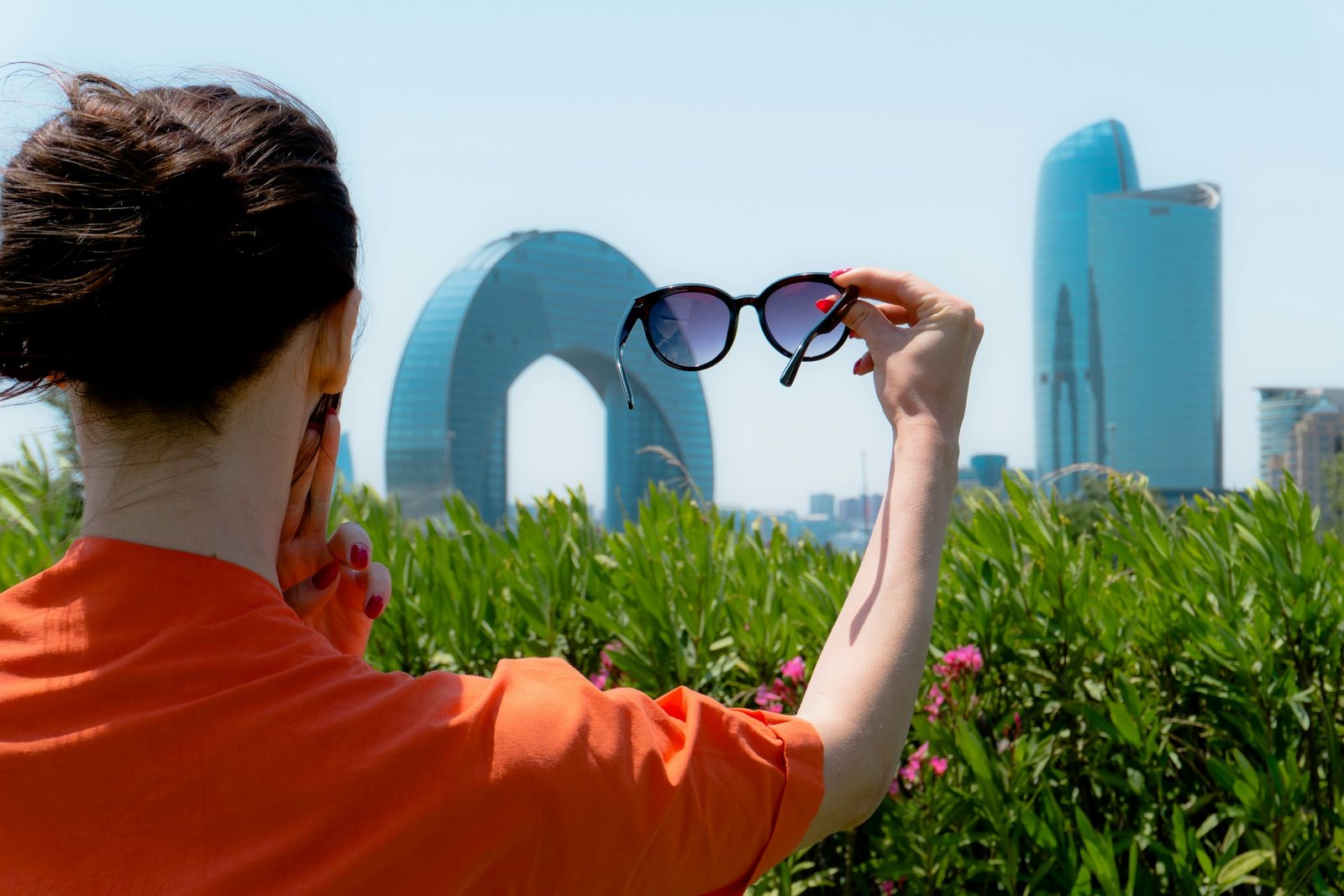 Woman holding up sunglasses against the city skyline