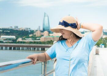 Woman in a straw hat and blue shirt on a terrace above the bay