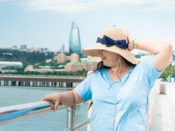 Woman in a straw hat and blue shirt on a terrace above the bay