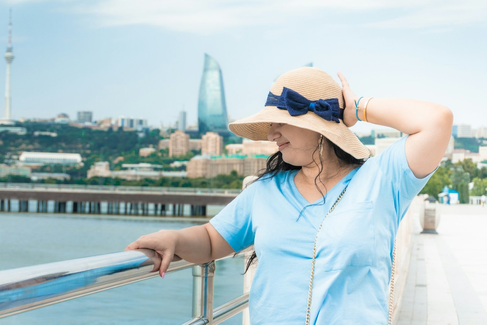 Woman in a straw hat and blue shirt on a terrace above the bay