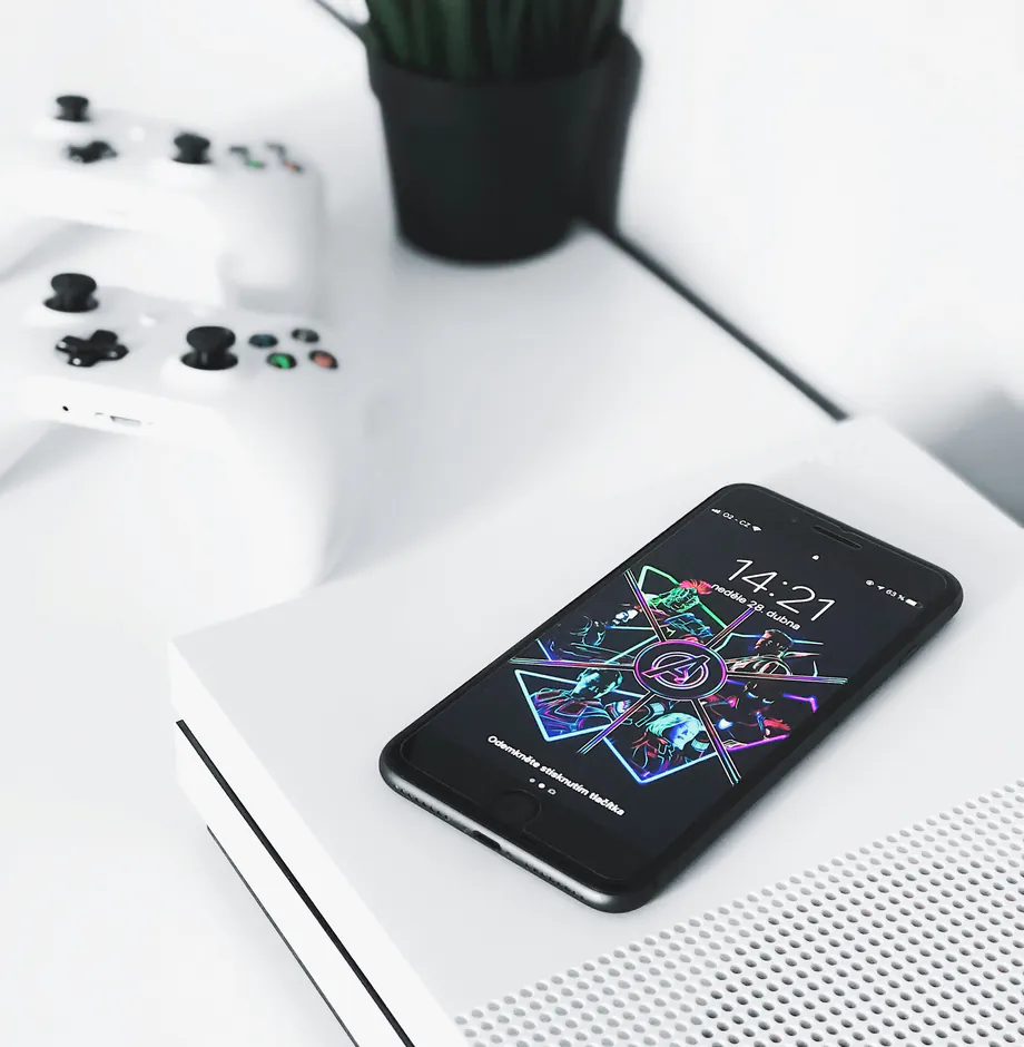 A phone with a neon lock screen lying on a white games console