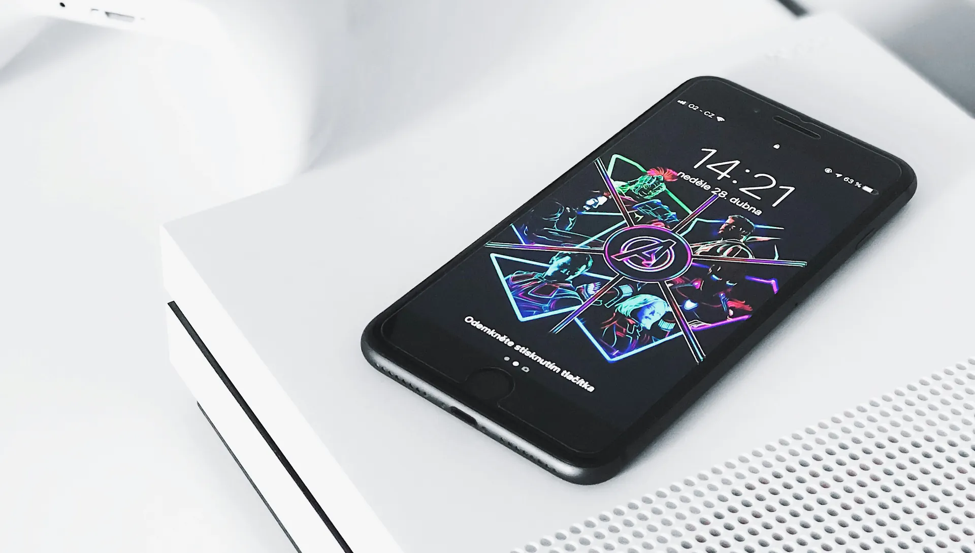 A phone with a neon lock screen lying on a white games console