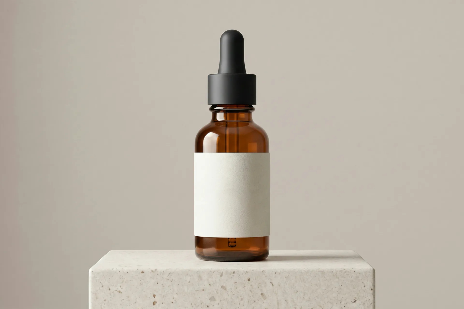 An amber glass dropper bottle with a blank white label, standing on a stone block
