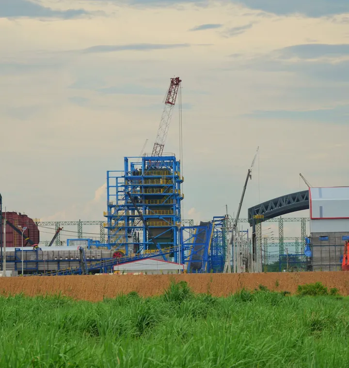 A blue steel boiler house under construction beside a green field