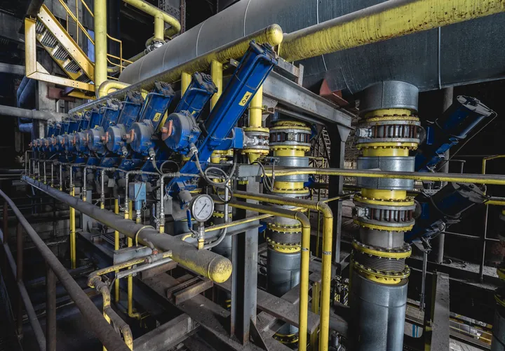 Blue pumps in a row along a pump-house floor, with yellow-lagged pipes overhead