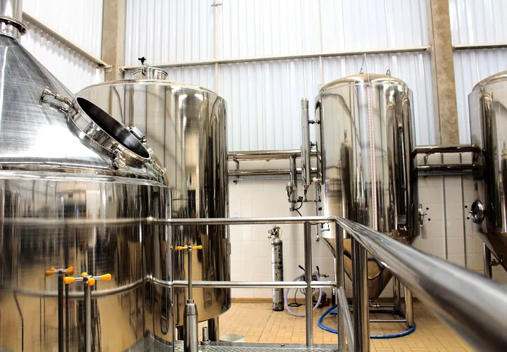 Polished stainless-steel process tanks and pipework in a white production hall