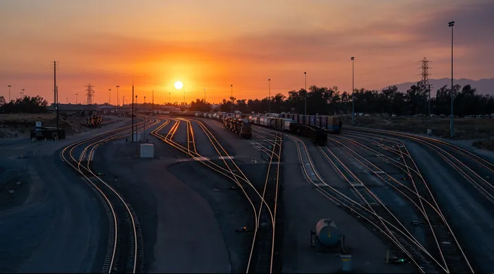 Rail tracks fanning out across a freight yard under an orange sunset