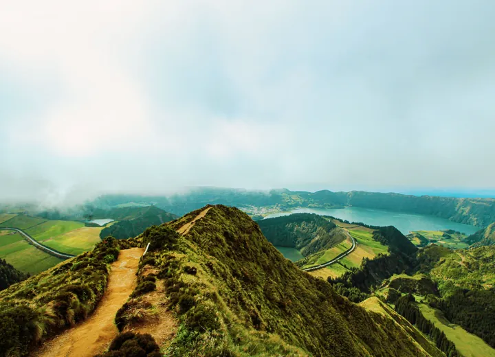 A walkers’ path along a green volcanic ridge on São Miguel, crater lakes and cloud beyond