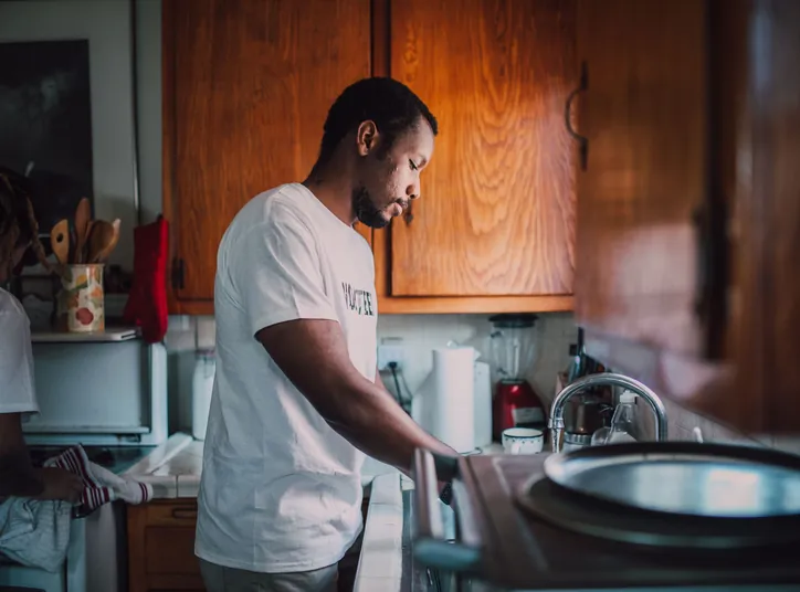 A volunteer washing up at a kitchen sink in a neighbor's home
