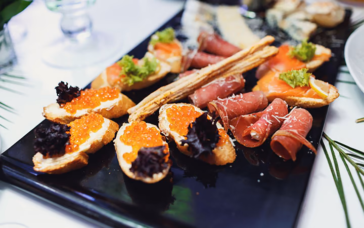 Canapes with caviar and cured ham on a dark slate