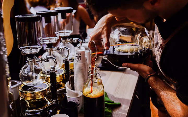 A bartender straining a cocktail into a glass