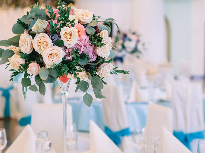 A tall arrangement of roses on a laid banquet table
