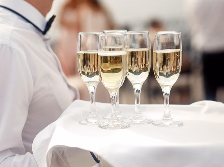A waiter carrying a tray of filled champagne flutes