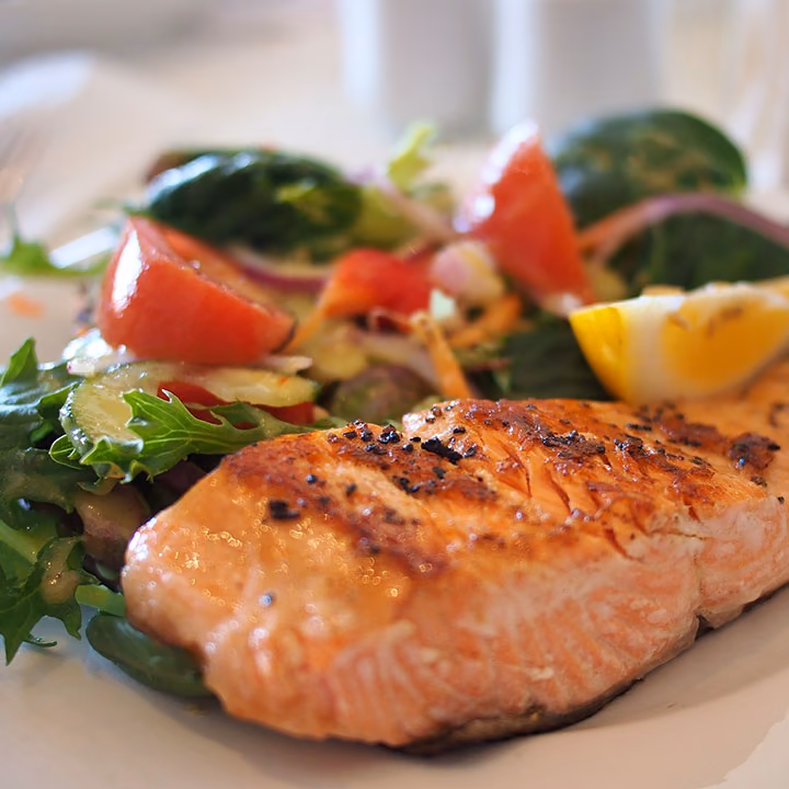 A grilled salmon fillet on a salad of tomato and rocket