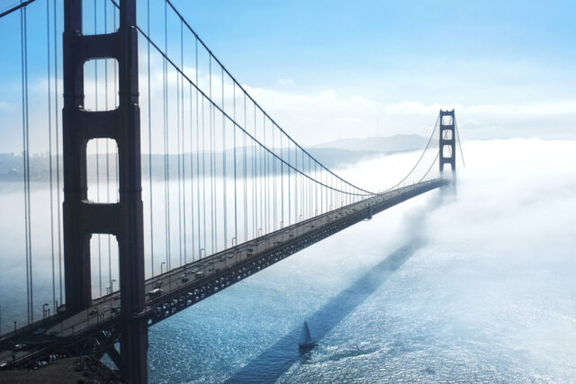 A suspension bridge fading into thick fog, only the near tower fully visible