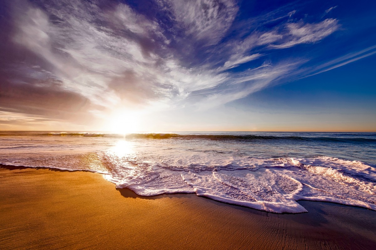 Warm sunset light over an ocean beach, waves blurred by a long exposure