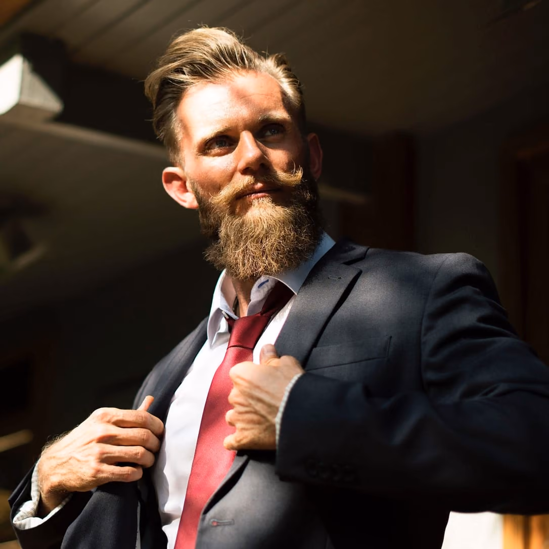Jeremy Scott, a bearded man in a dark suit and red tie