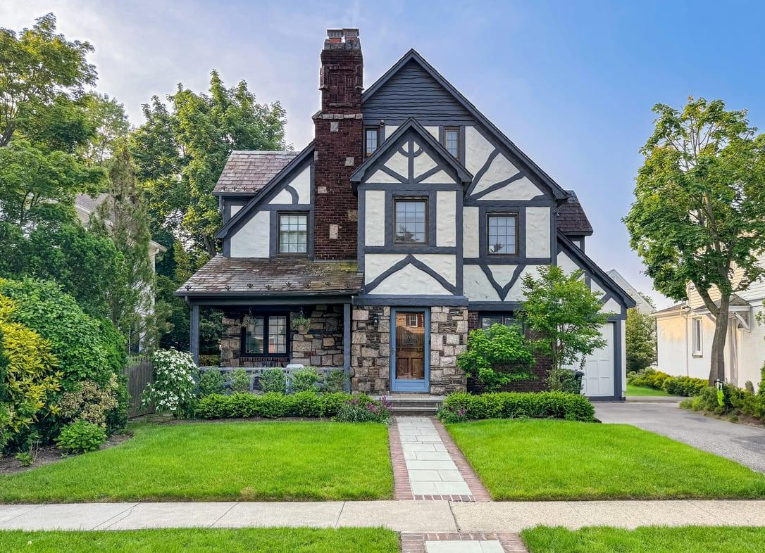 Tudor-style house with white half-timbered gables, a stone porch and a front lawn