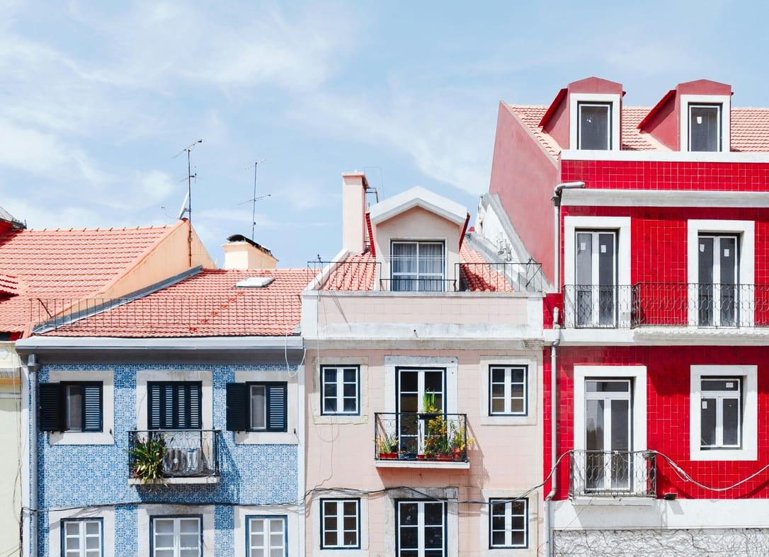 Row of old townhouses with blue and white tiles, a red facade and wrought-iron balconies