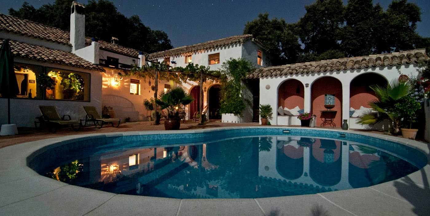 White Mediterranean villa with arched loggias around a lit swimming pool at night