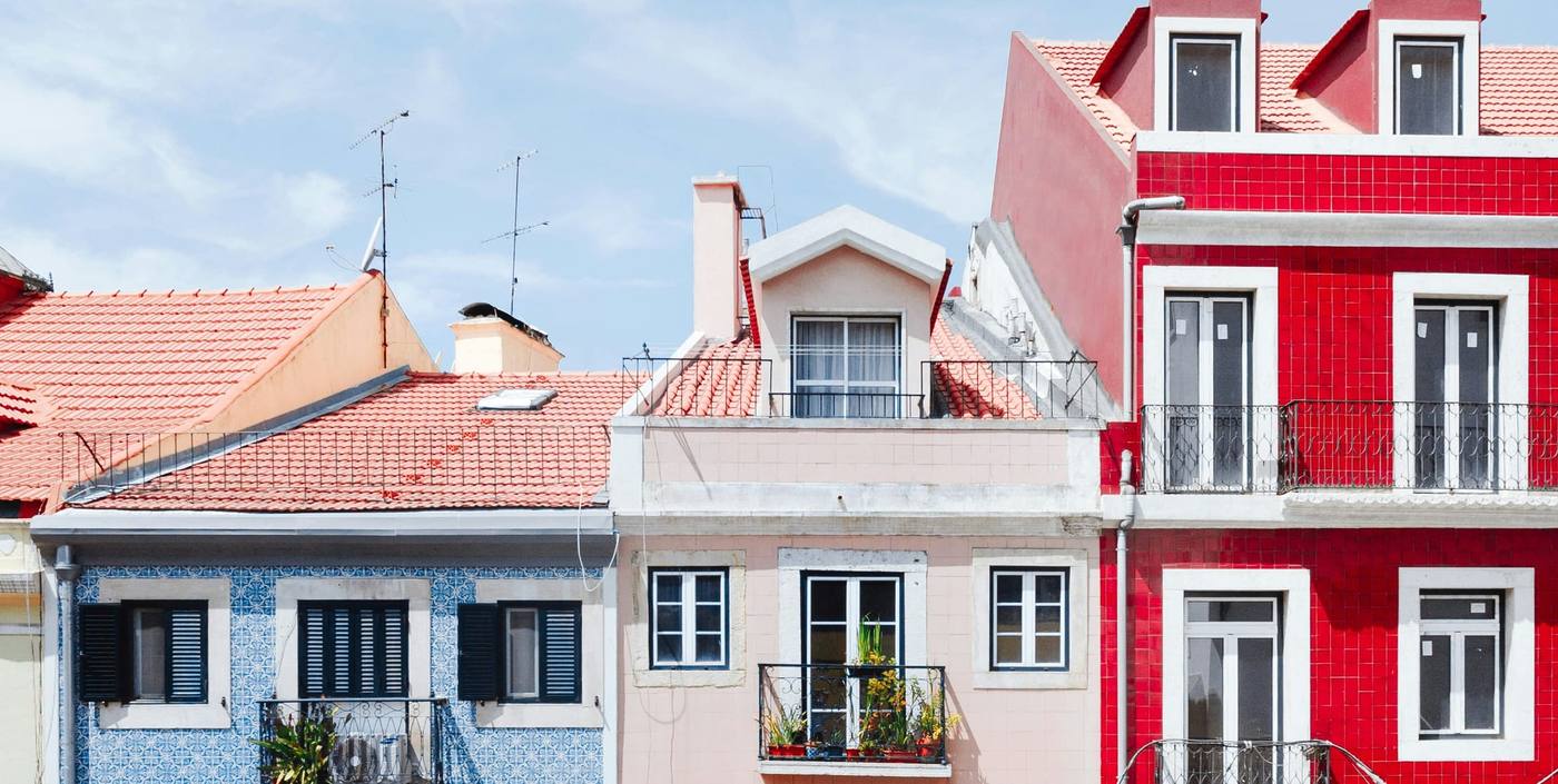Row of old townhouses with blue and white tiles, a red facade and wrought-iron balconies