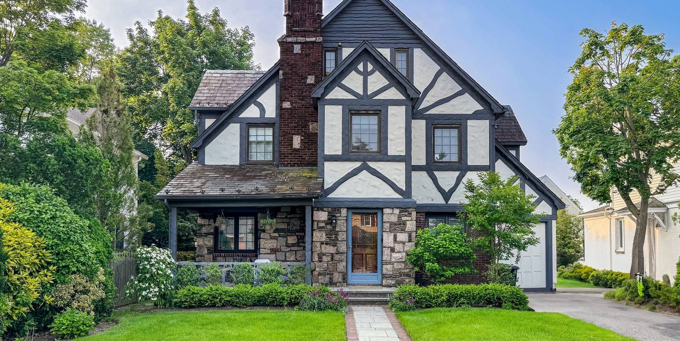 Tudor-style house with white half-timbered gables, a stone porch and a front lawn