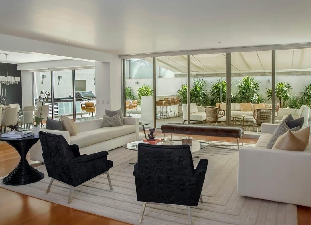Open-plan living room with black armchairs, white sofas and floor-to-ceiling glass