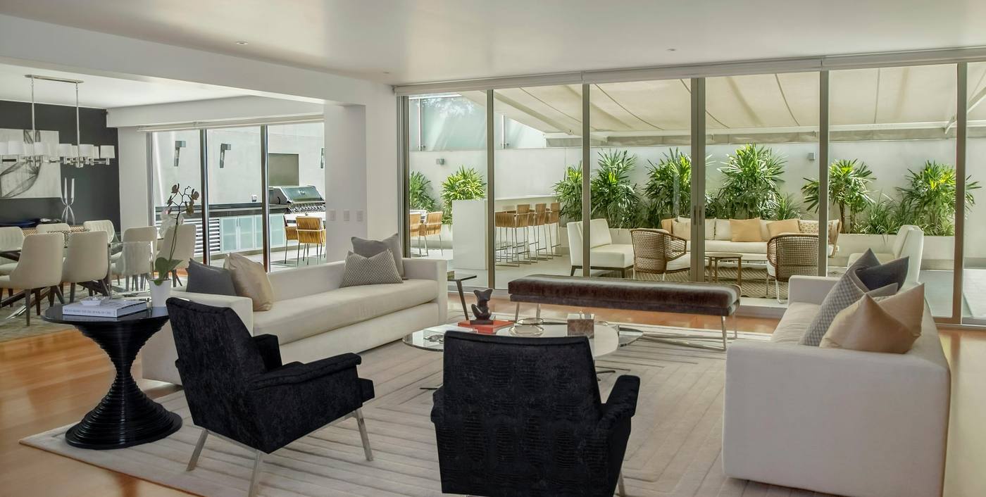 Open-plan living room with black armchairs, white sofas and floor-to-ceiling glass