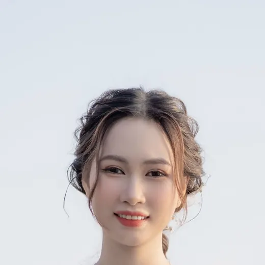 Mai with her hair up and a pearl clip, smiling at the camera