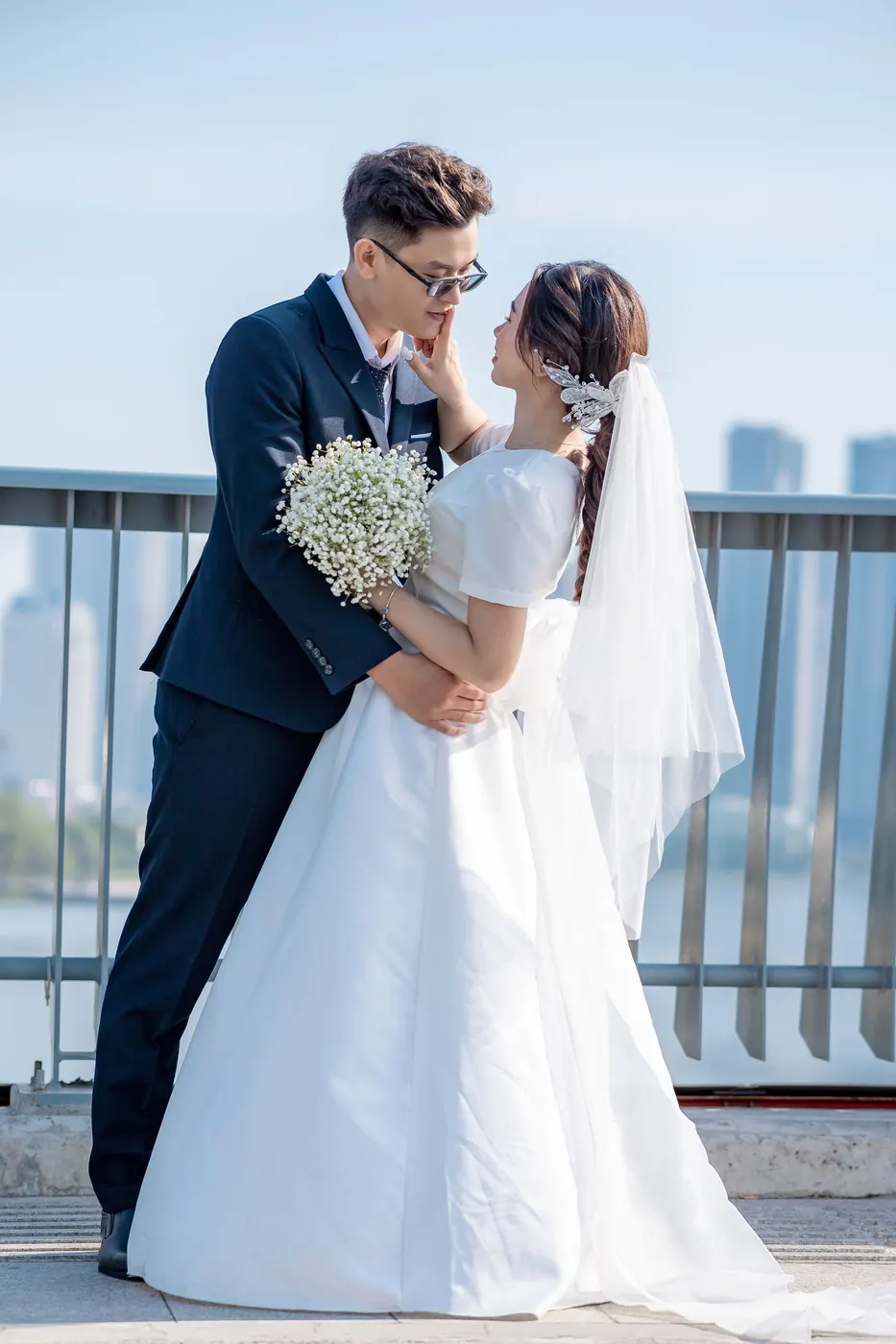 Khoa holding Mai close on the bridge, her head against his shoulder