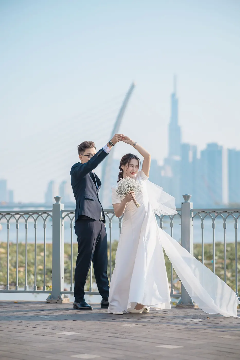 Khoa lifting Mai’s hand to twirl her on the bridge, her veil flying, the city’s towers behind
