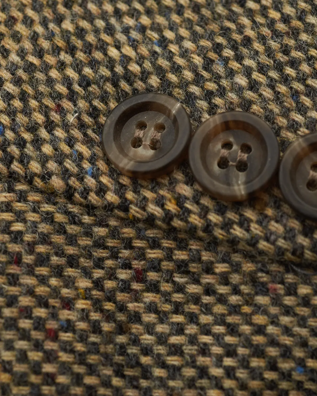 Horn buttons on the cuff of a tweed jacket