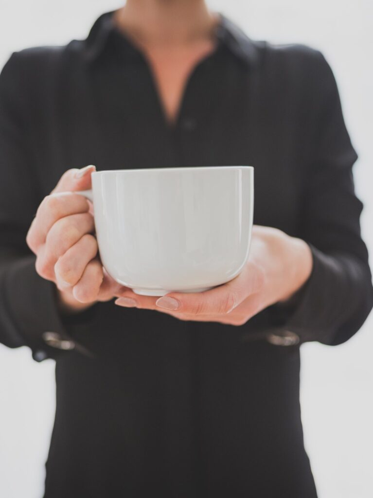 A woman in a black shirt holding a white cup